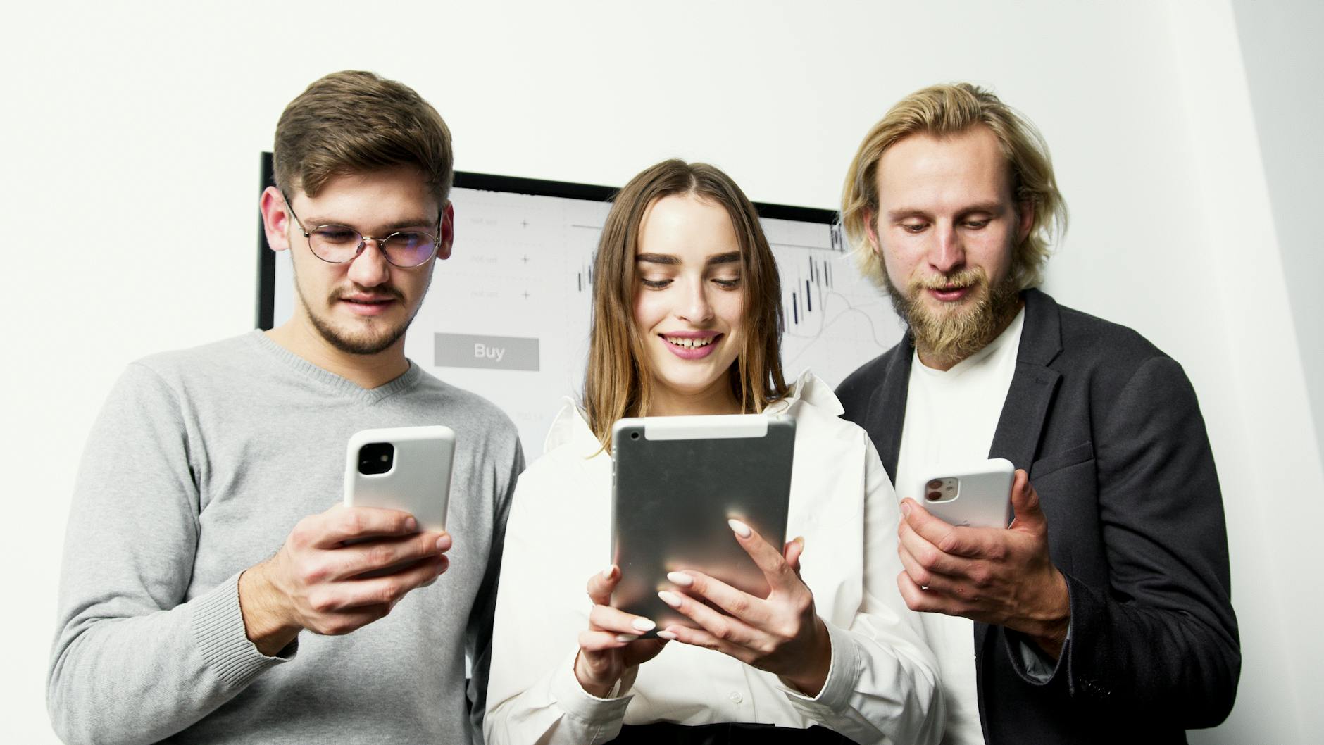 Three professionals using digital devices for financial analysis in an office setting.