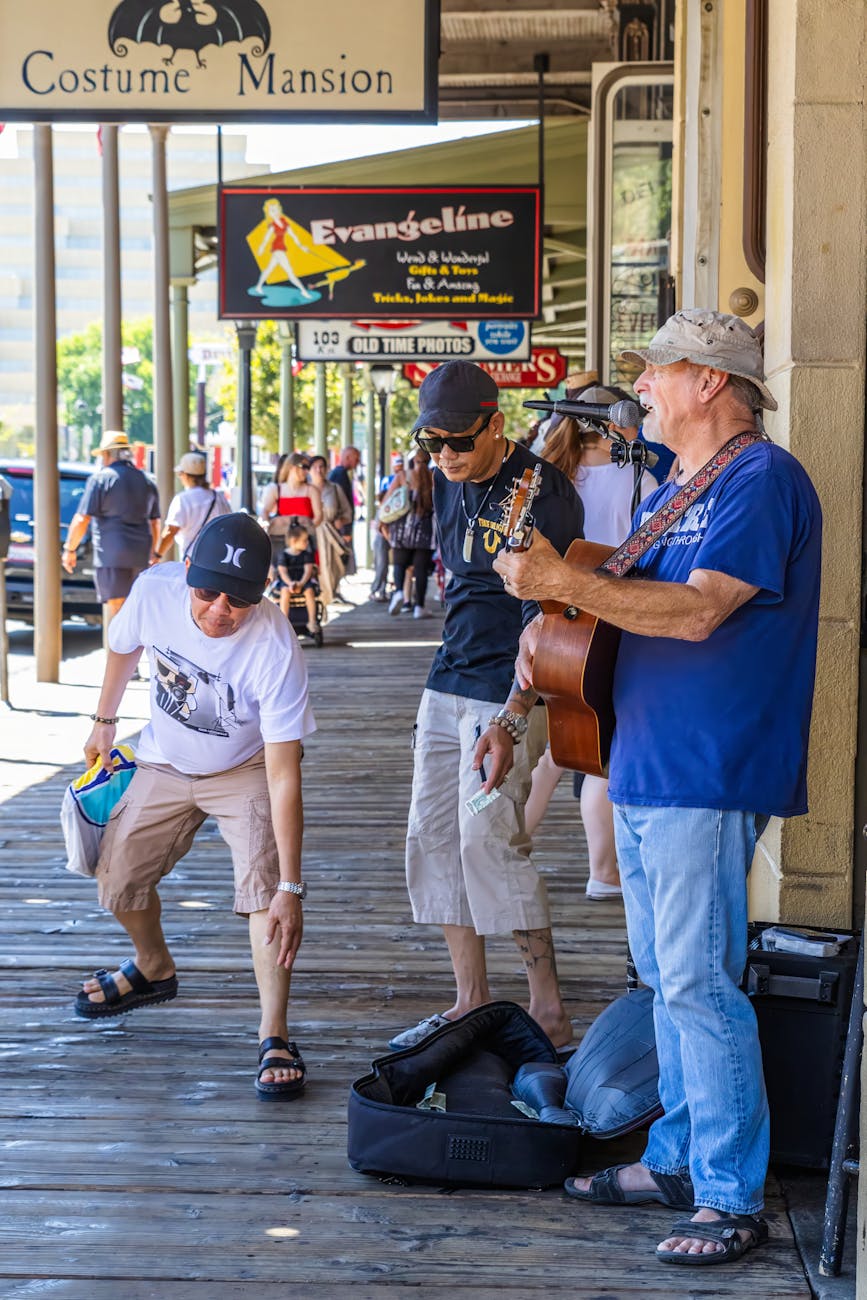 Elderly street performer playing guitar captivating urban crowd in lively outdoor setting.