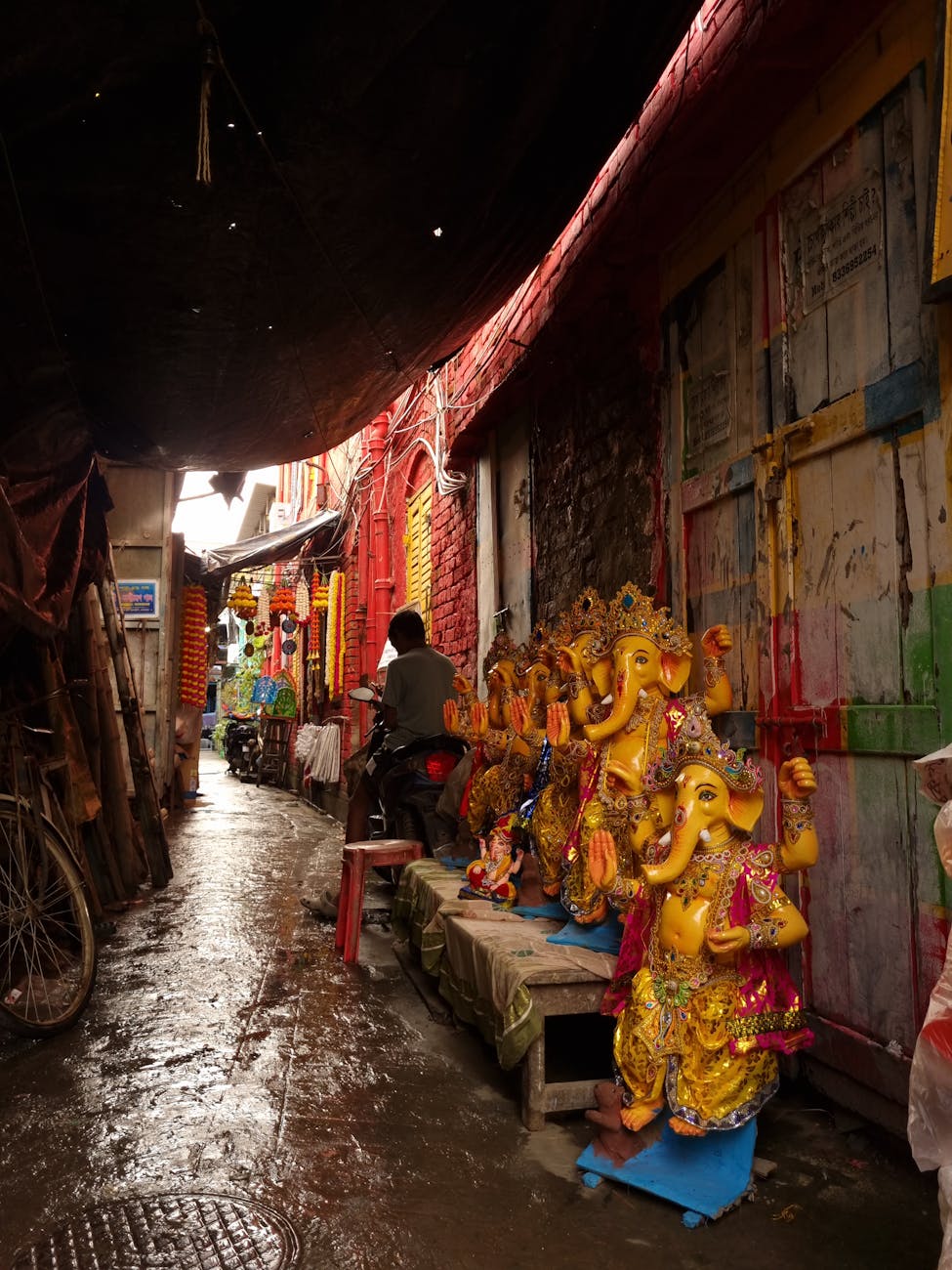 Colorful Ganesh statues brighten a narrow alley in India, capturing cultural vibrance.