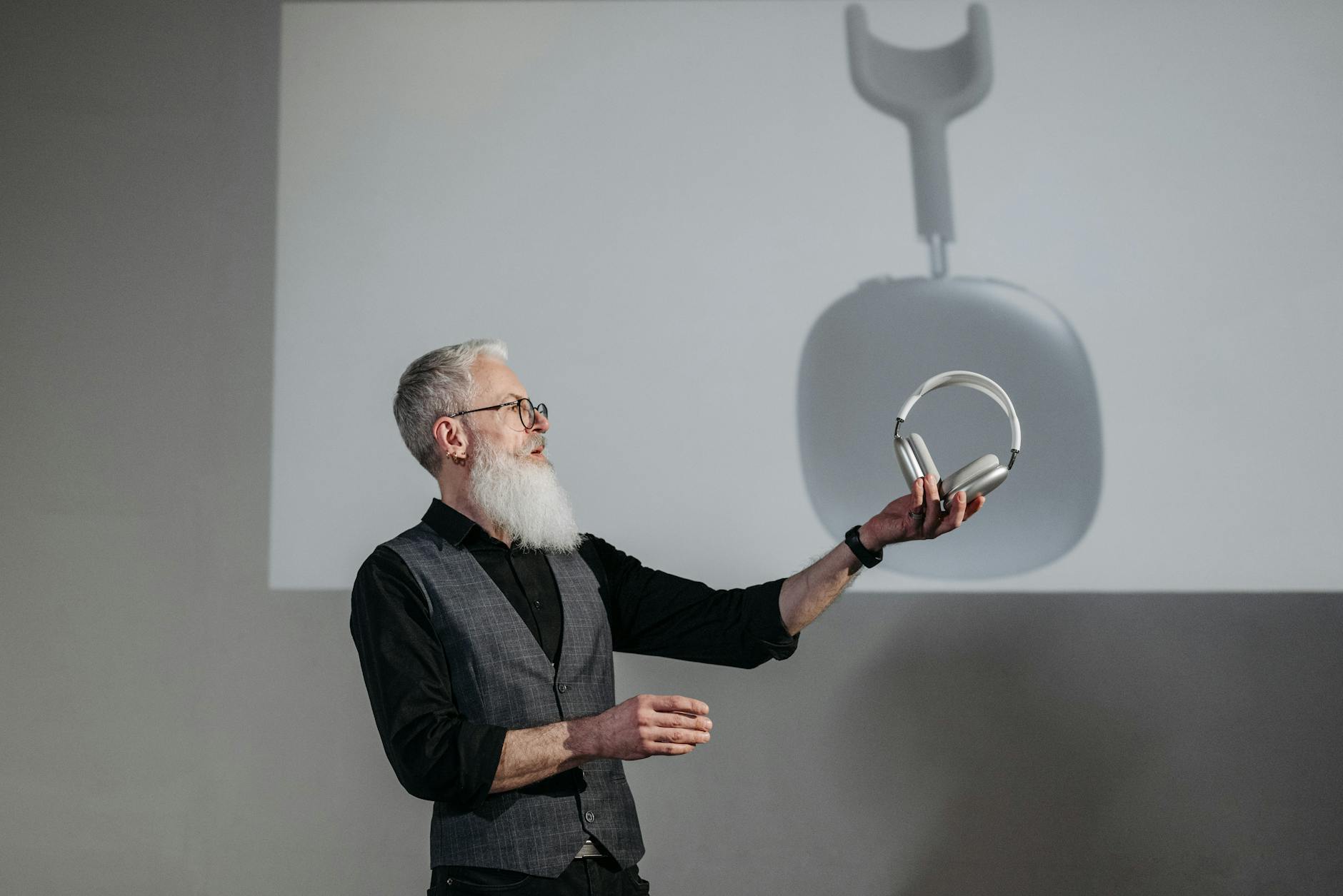 Mature man presenting wireless headphones in a business setting.